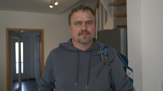 Klaus, getrennter Vater. Klaus trägt einen blauen Hoodie, über seiner linken Schulter hängt locker ein Kinderrucksack. Er schaut mit traurigen Augen in die Kamera. 