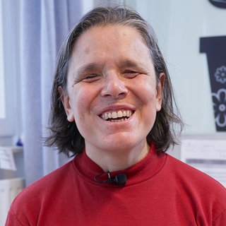 Cristina ist zufrieden mit ihrem Beruf als MTU in der Brustkrebsfrüherkennung und grinst in die Kamera.