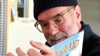 Ex-Gastronom Frieder ist heute Erzieher. Er liest den Kindern eine Geschichte aus einem Buch vor.