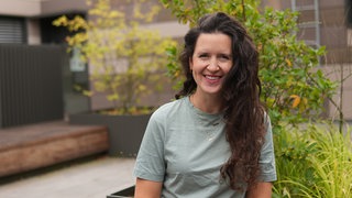 Frau mit grünem T-Shirt und dunklen Locken.