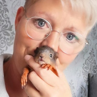 Junge Frau, mit kurzen Haaren und Eichhörnchen in der Hand