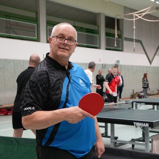 Älterer Herr mit Tischtennisschläger vor Platte