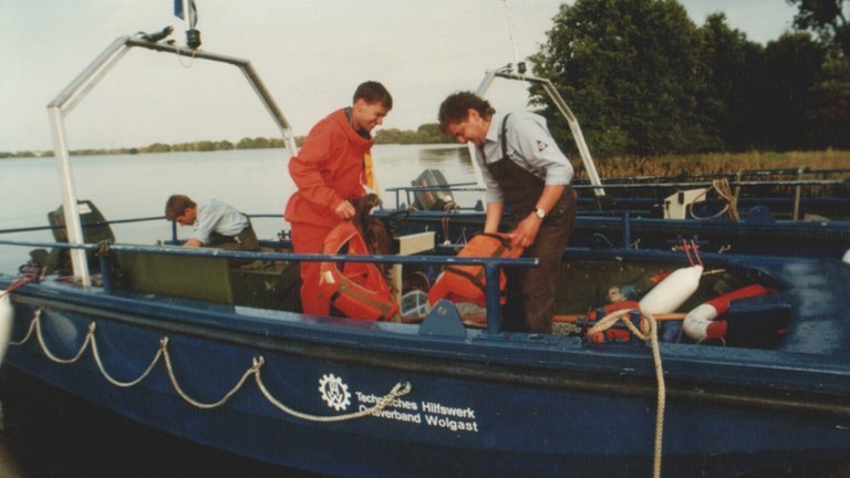Helfer des THW bei Vorbereitungen für einen Einsatz auf einem Boot.
