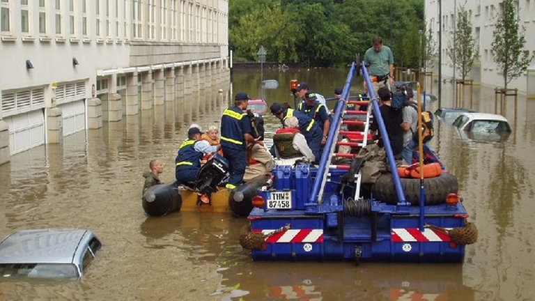 Ein Boot des Technischen Hilfswerks fährt durch überflutete Straßen