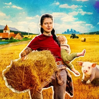 Victoria mit Baby und Strohballen auf dem Arm neben ihr ein Schwein auf Korngelber Wiese im Hintergrund eine Dorfkirche.