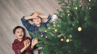 Zwei Kinder unter dem Weihnachtsbaum