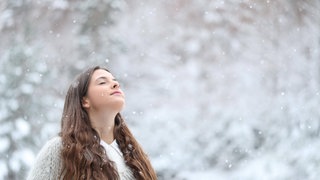 Frau atmet entspannt im Schnee