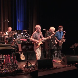 Eine Band, bestehend aus sechs Musikern, performt live auf einer Bühne