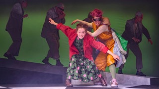 Momo (Hannah Im Hof), Schildkröte Kassiopeia (Linda Schlepps), im Hintergrund die Grauen