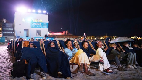 Während der 78. Internationalen Filmfestspiele in Cannes, Südfrankreich, sehen sich Menschen einen Film am Strand an.
