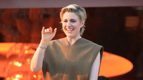 Greta Gerwig winkt an einer Balustrade