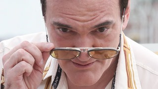 Quentin Tarantino 2019. Er neigt den Kopf nach vorne und schaut uns über seine Sonnenbrille hinweg an