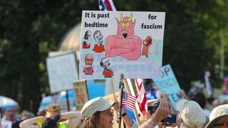 Ein Demonstrant hält ein Anti-Trump-Plakat bei der Protestkundgebung „Rage Against the Regime“ vor dem Kapitol von Pennsylvania in Harrisburg am 2. August 2025.