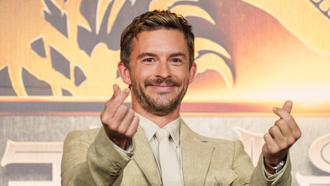 Jonathan Bailey zeigt Herz-Symbole bei der Asien-Premiere von „Jurassic World: Rebirth“.