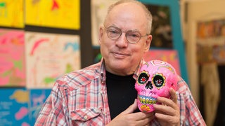 Filmregisseur Rosa von Praunheim hält am 08.11.2017 in seiner Wohnung in Berlin einen Totenkopf in die Kamera.