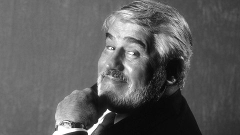 Mario Adorf im Halbprofil mit einem Lächeln dem Zuschauer zugewandt.