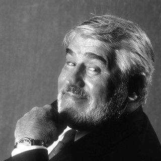 Mario Adorf im Halbprofil mit einem Lächeln dem Zuschauer zugewandt.