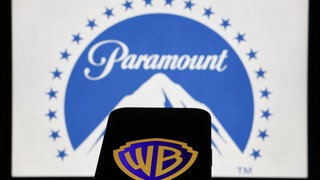 Das Paramount-Logo auf einem Laptop-Bildschirm und das Warner Bros-Logo auf einem Telefonbildschirm.
