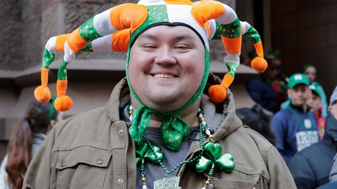 Ein Mann trägt bei der Saint Patrick's Day Parade in New York einen lustigen Hut in den irischen Farben grün, weiß und orange. Orange steht dabei für die protestantische Bewegung, wohingegen das Grün die Katholiken repräsentieren soll.