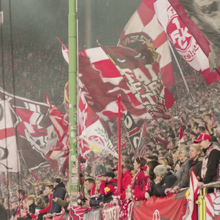 Die Fans des 1. FC Kaiserslautern feiern ihren Verein mit wehenden Fahnen.