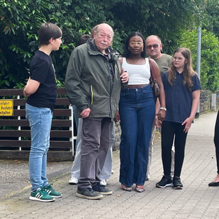 Alter Mann steht mit seinen Enkeln auf der Straße