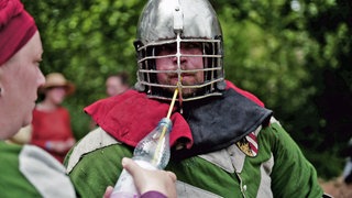Ritter trinkt beim Spectaculum Worms mithilfe eines Strohhalms durch sein Helmgitter aus einer Wasserflasche