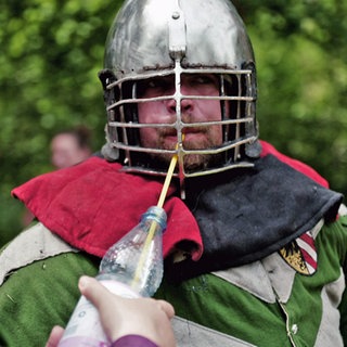 Ritter trinkt beim Spectaculum Worms mithilfe eines Strohhalms durch sein Helmgitter aus einer Wasserflasche