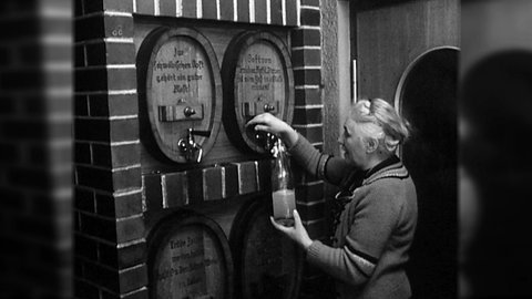 Eine Frau füllt Most aus einem Fass in eine Falsche - schwarz-weiß-Bild
