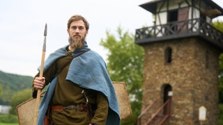 Finnian Garvey steht vor dem Limesturm Nr. 1 am Deutschen Limes-Wanderweg.