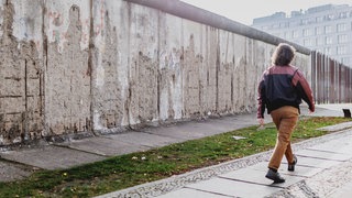 Eine Frau läuft an Überresten der Berliner Mauer an der Bernauer Strasse vorbei.