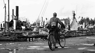 Ein Soldat mit einem Fahrrad an der Kreuzung von Rovakatu und Hallituskatu Regierungstraße in der nördlichen finnischen Stadt Rovaniemi, die nach deutschen Bombenangriffen im Zweiten Weltkrieg 1944 in Trümmern liegt.