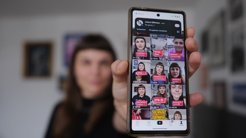 Susanne Siegert hält ein Smartphone und zeigt ihren Kanal