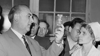 Der stellvertretende Vorsitzende des Ministerrats, Vorsitzende der Staatlichen Plankommission der DDR Erich Apel (vorn) trifft die Arbeiterin A. Timonina im Moskauer Elektrizitätslampenwerk.