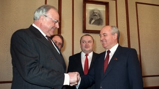 Bundeskanzler Helmut Kohl (l) und der sowjetische Staatschef Michail Gorbatschow schütteln sich im Beisein von Dolmetschern am 10.2.1990 in Moskau die Hände. Die Sowjetunion respektiert die Entscheidung der Deutschen für eine Wiedervereinigung.