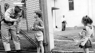 Ein Militärpolizist der US-Armee spricht am 19.07.1963 vor einer Kaserne in Bad Kreuznach mit zwei kleinen Kindern.