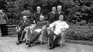 Potsdamer Konferenz - (v.l.n.r.) Clement Attlee, US-Präsident Harry S. Truman, Josef Stalin; stehend dahinter: US-Admiral William Daniel Leahy, Ernest Bevin und US-Außenminister James F. Byrnes