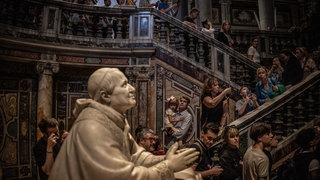 Pilger gehen an der Marmorstatue von Papst Pius IX. in der Basilika Santa Maria Maggiore vorbei.
