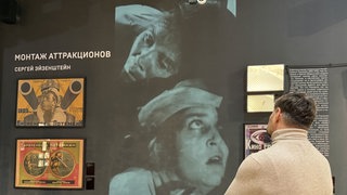 Im Moskauer Kinomuseum wird der Kultfilm «Panzerkreuzer Potemkin» von Sergej Eisenstein gewürdigt. Ein Ausstellungsbesucher schaut sich an einer Wand einen Filmausschnitt neben den Kinoplakaten zum Film an.