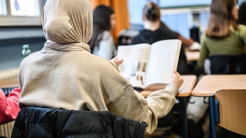Eine Schülerin mit Kopftuch symbolbildlich für Kinder mit Migrationshintergrund, die bessere Noten erhalten.