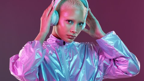 Hologramm-Frau hört Musik. In wenigen Sekunden generiert Künstliche Intelligenz neue Musik. Menschen, die mit dem Komponieren Geld verdienen, machen sich Sorgen. Aber zurecht? Ein neues Experiment aus Hannover liefert Antworten.