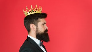 Mann im schwarzen Anzug trägt Krone auf dem Kopf: Der Soziologe Christopher Lasch sprach 1979 vom "Zeitalter des Narzissmus",  die Psychologin Jean Twenge bestätigte 2008 in einer umfangreichen Untersuchung eine "Narzissmusepidemie". Wie ist der Forschungsstand heute? Werden die Menschen immer narzisstischer?