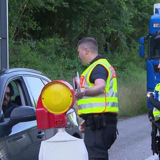 Polizisten:innen führen eine Grenzkontrolle durch