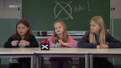 drei Kinder hinter der Schulbank