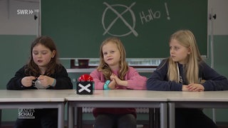 drei Kinder hinter der Schulbank