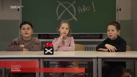 drei Kinder vor einer Schultafel