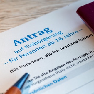 Nahaufnahme von einem Antrag auf Einbürgerung in die Bundesrepublik Deutschland und ein deutscher Reisepass