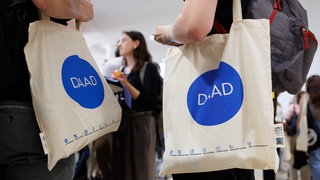 Studenten tragen Taschen des DAAD bei einem Treffen Internationaler Studierenden.