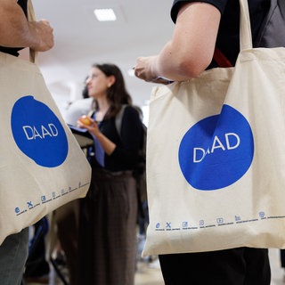 Studenten tragen Taschen des DAAD bei einem Treffen Internationaler Studierenden.