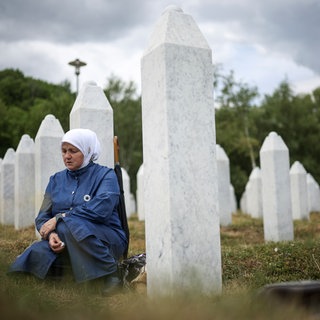 Eine bosnische Muslimin trauert neben dem Grab ihres Verwandten, eines Opfers des Völkermords von Srebrenica, vor der Massenbegräbniszeremonie.