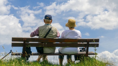 Zwei Rentner sitzen auf einer Bank und schauen in die endlose Weite 